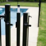 Black aluminium pool gate left slightly open with the latch missing the striker, showing a gate that has stopped self-closing